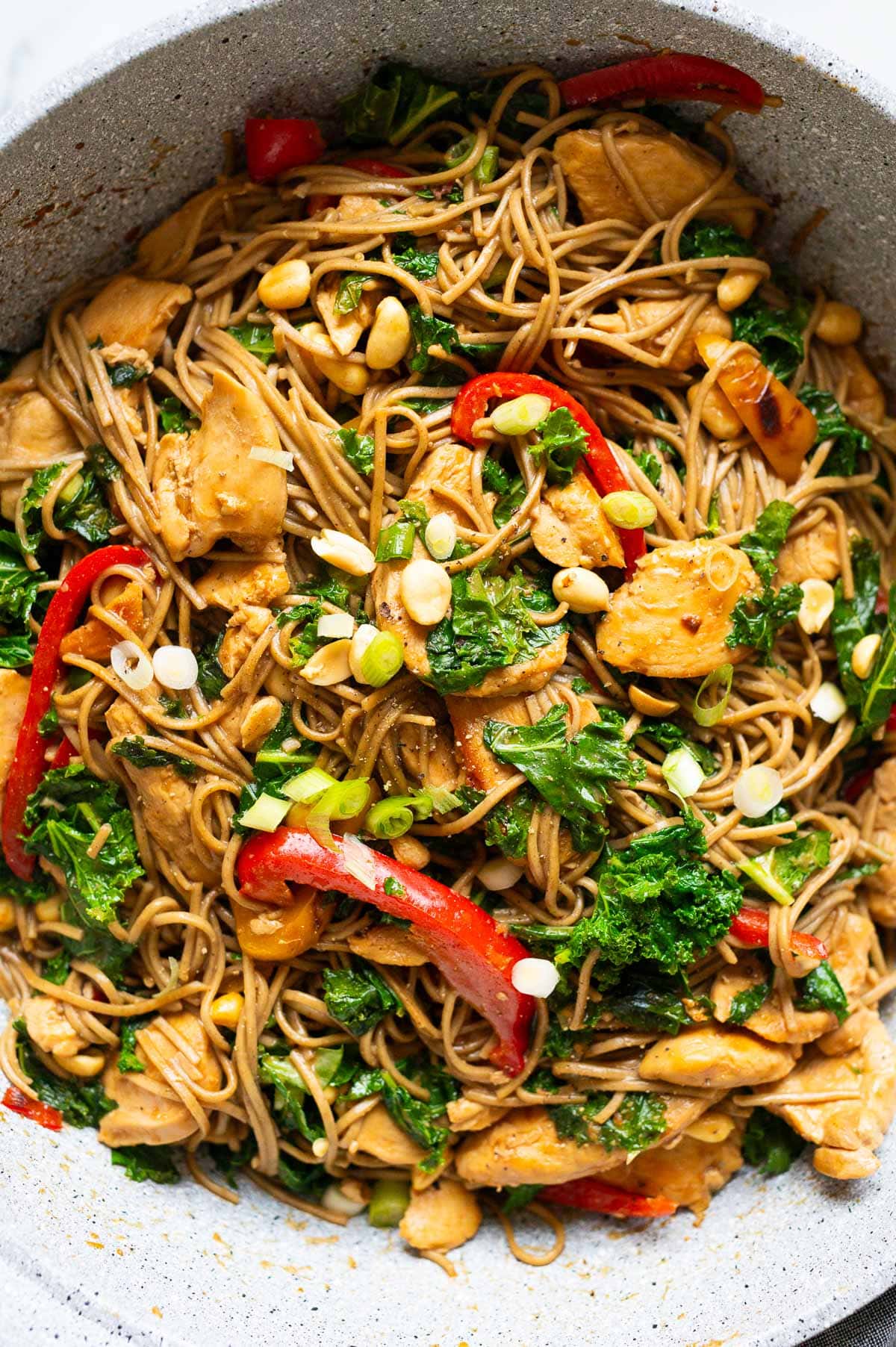 Close up of chicken soba noodles stir fry with kale, bell peppers and peanuts.