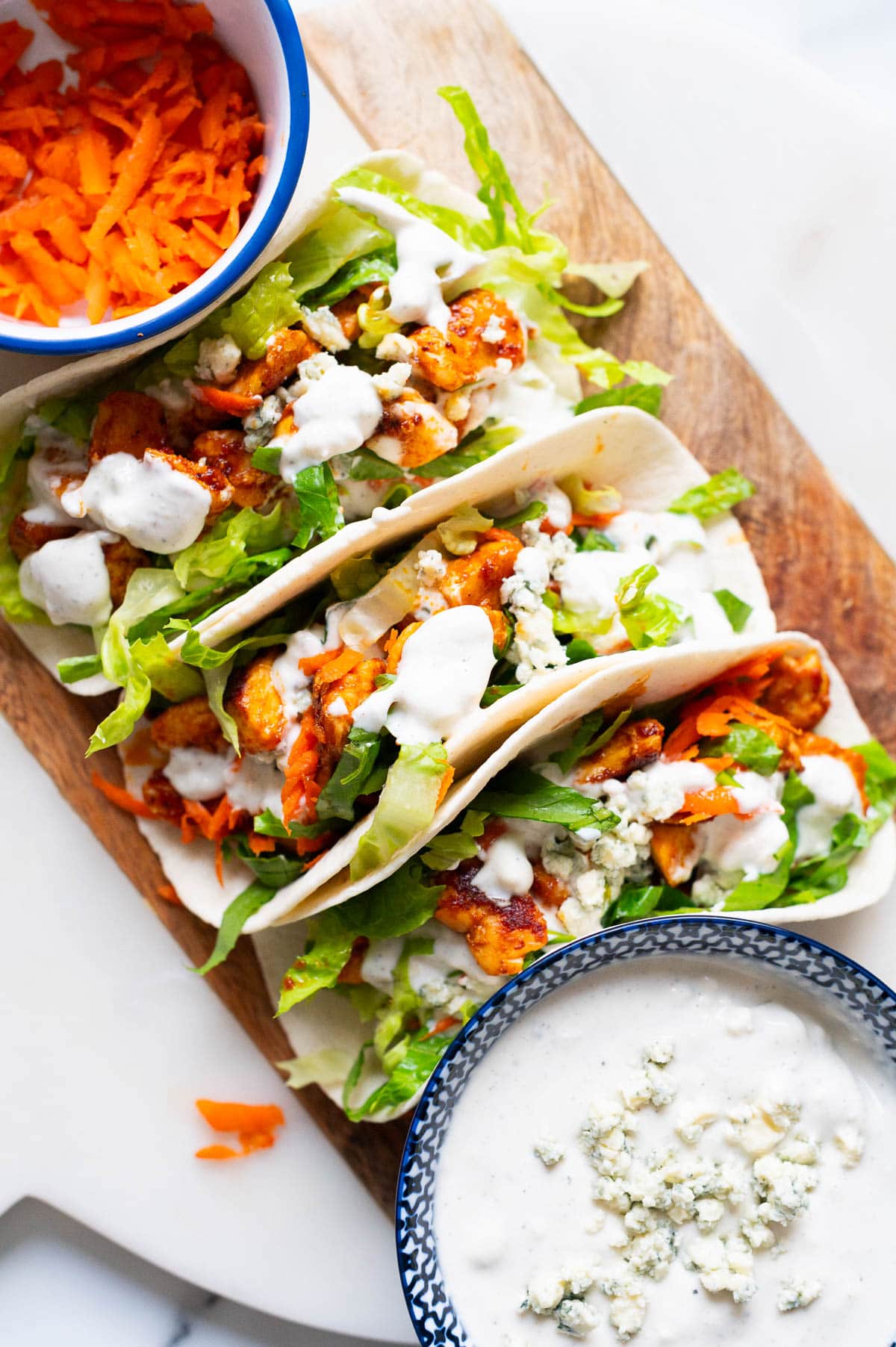 Buffalo chicken tacos with shredded carrots, lettuce and blue cheese dressing.