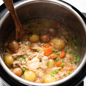 Chicken stew in instant pot with wooden spoon.