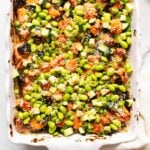 Salmon sushi bake with edamame beans, cucumber, green onion and sesame seeds in a baking dish.