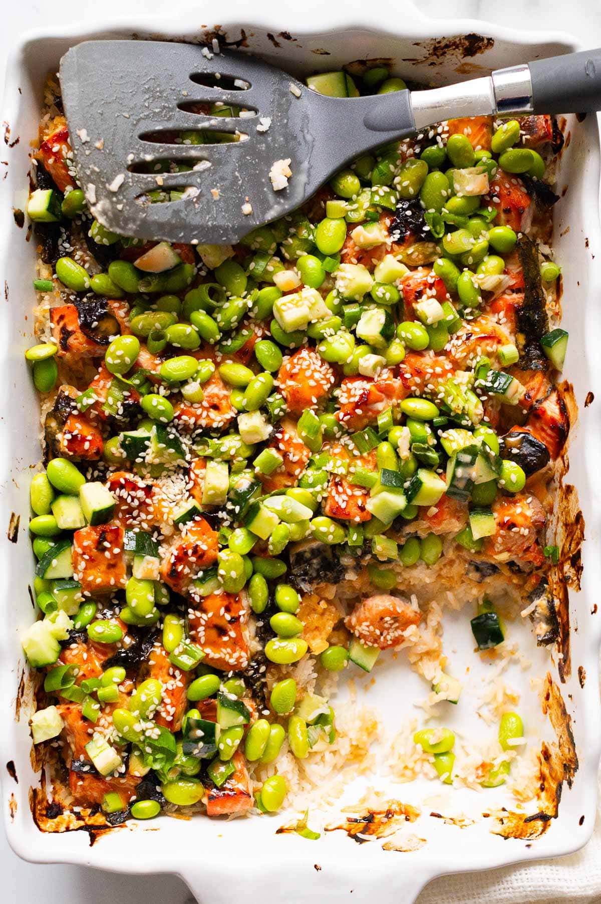 Salmon sushi bake showing texture in a baking dish with serving spatula.