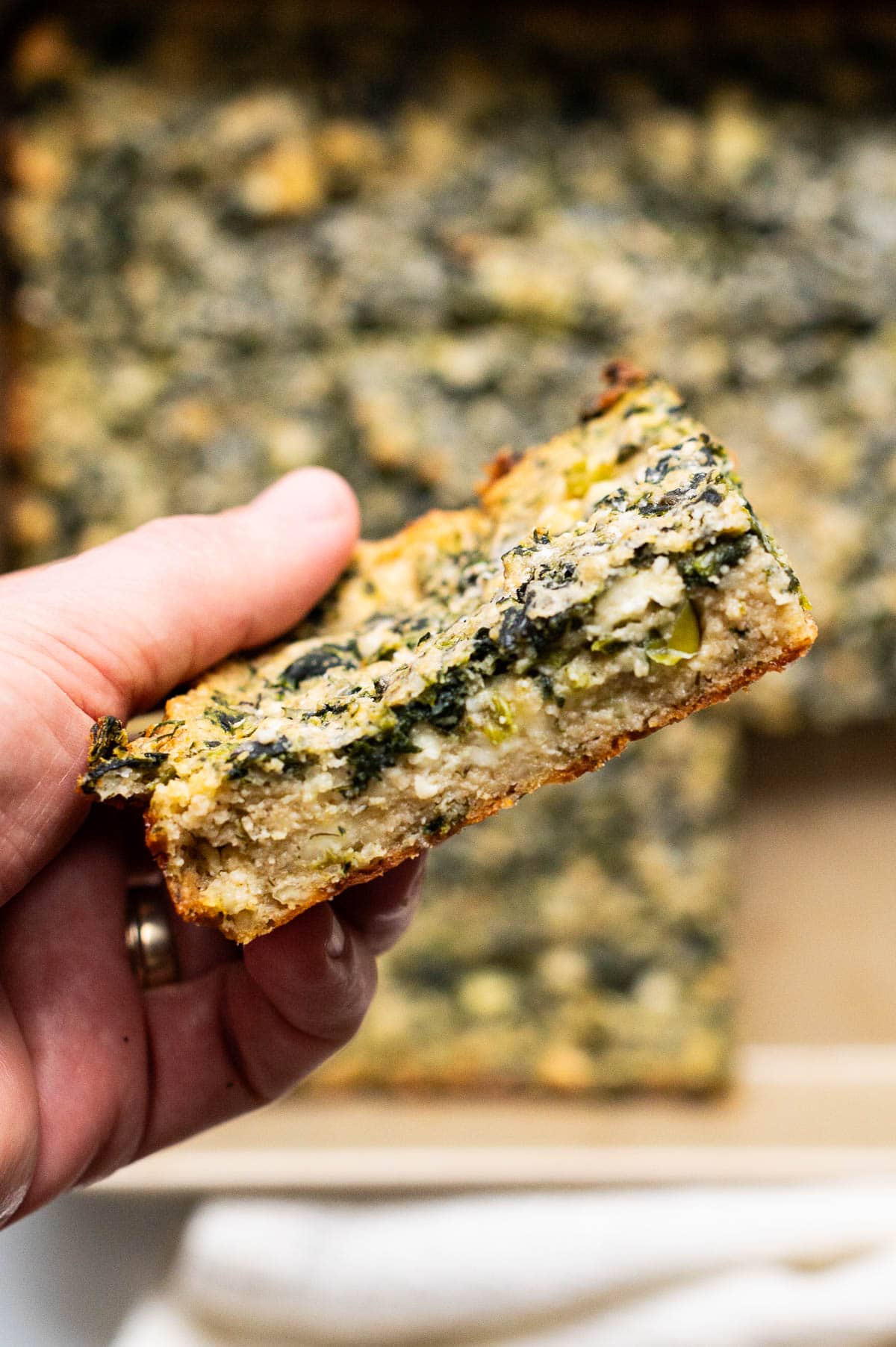 Person holding a spinach brownie showing texture inside.
