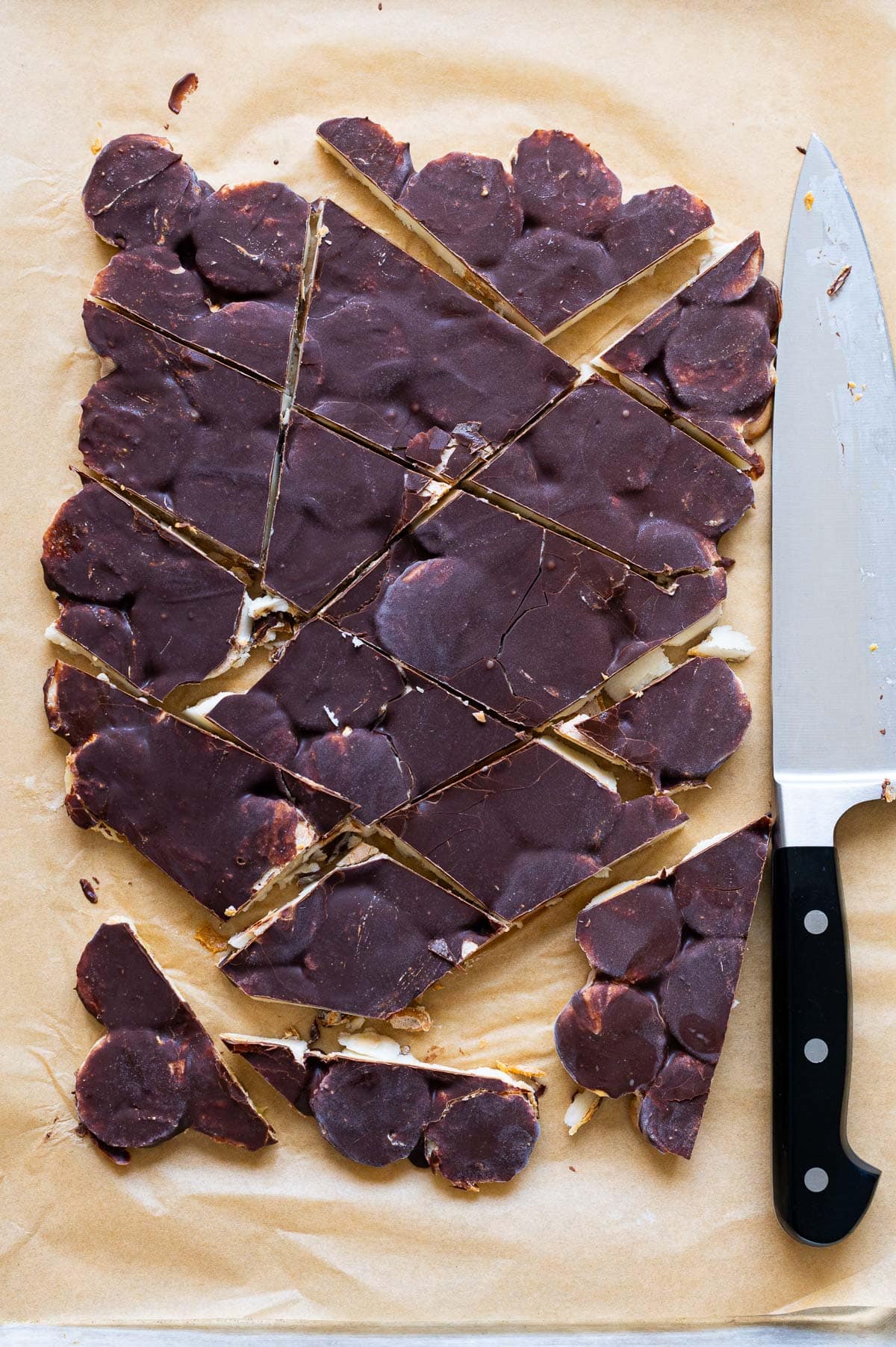 Sliced banana peanut butter bark on parchment paper with knife next to it.