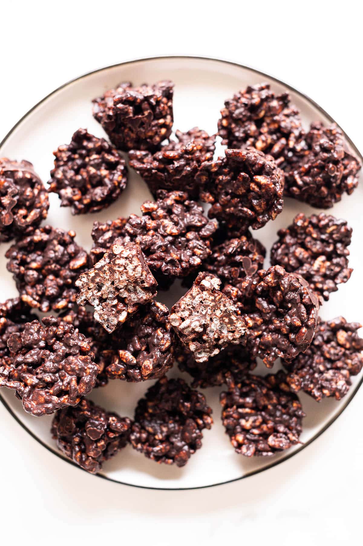 Chocolate rice krispie treats on a plate with one cut in half showing texture.