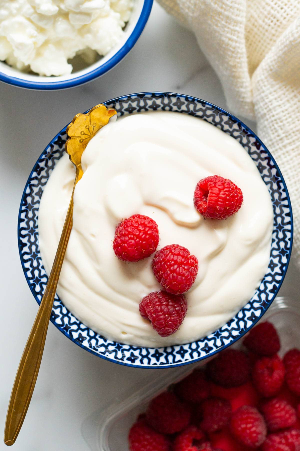 Cottage cheese pudding garnished with fresh raspberries in a serving bowl with a spoon.