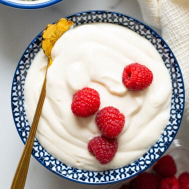 Cottage cheese pudding garnished with fresh raspberries in a serving bowl with a spoon.