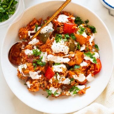 Deconstructed stuffed peppers served in a bowl with sour cream and parsley.