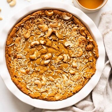 Healthy breakfast cake garnished with cashews and coconut flakes in a baking dish.