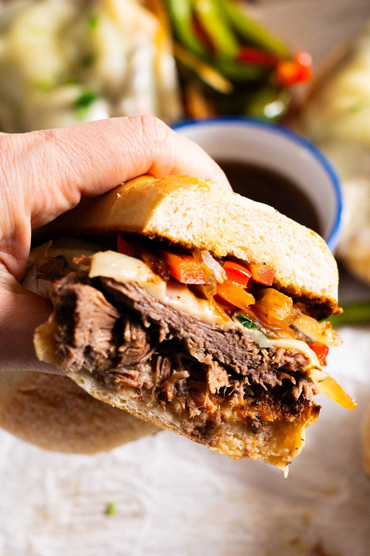 Person holding sliced instant pot French dip sandwich showing texture inside.