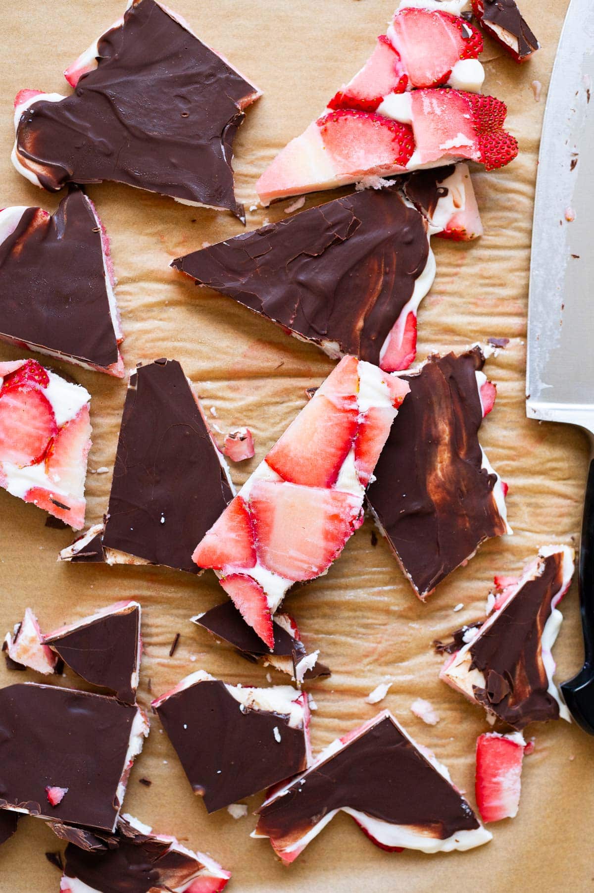 Strawberry bark cut into slices on parchment paper. Knife nearby.