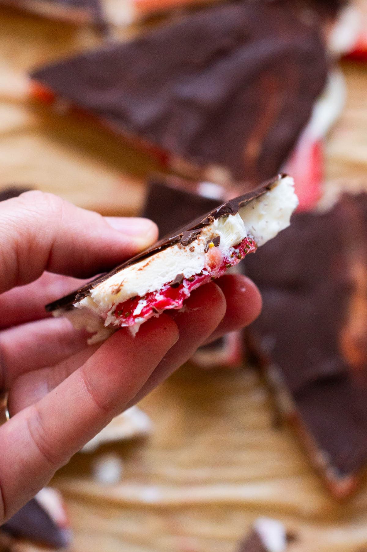Person holding a slice of strawberry bark.