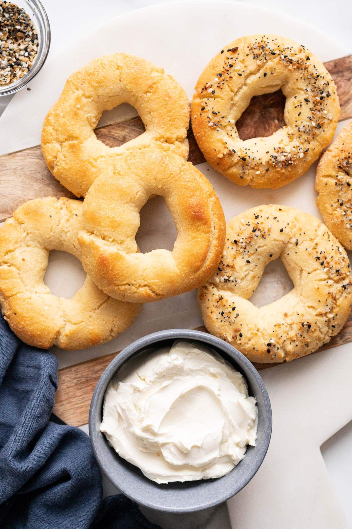 6 almond flour Greek yogurt bagels. Some with everything bagel seasoning on top. Cream cheese in a bowl.