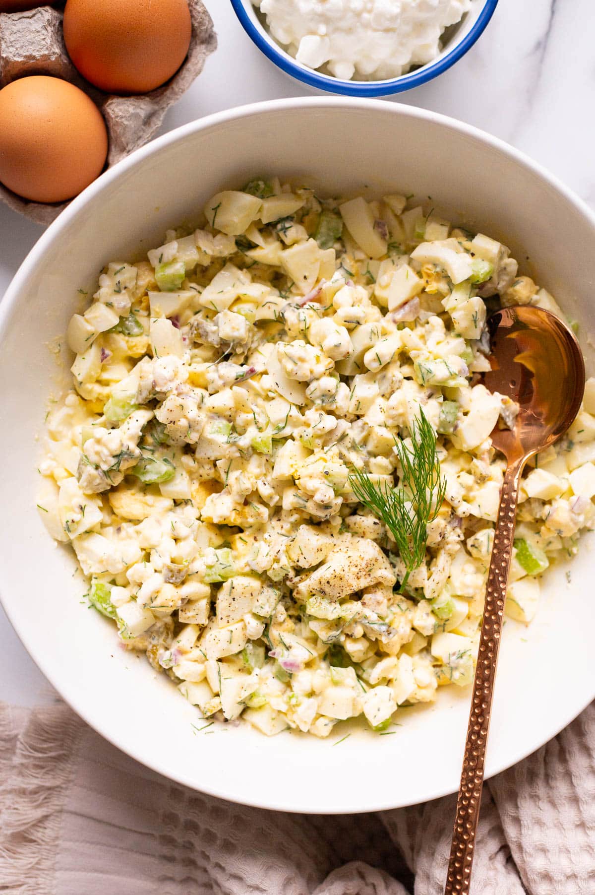 Cottage cheese egg salad in a bowl with a spoon. Eggs and cottage cheese on a counter. 