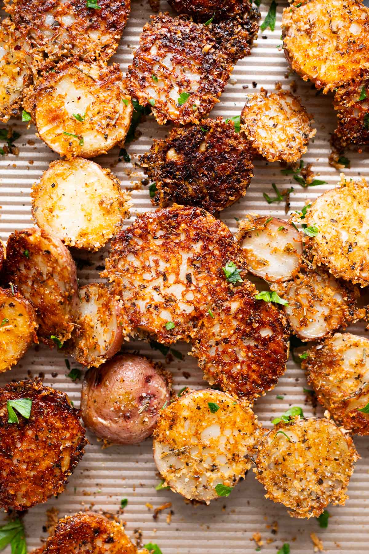 Crispy Parmesan potatoes garnished with parsley on a baking sheet.