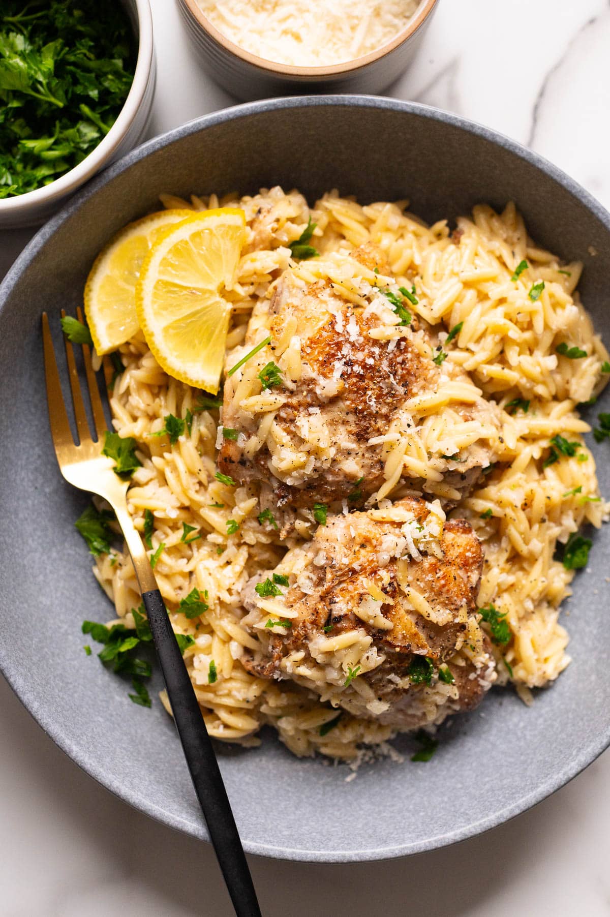 Lemon chicken orzo served on a plate and garnished with lemon slices and parsley.
