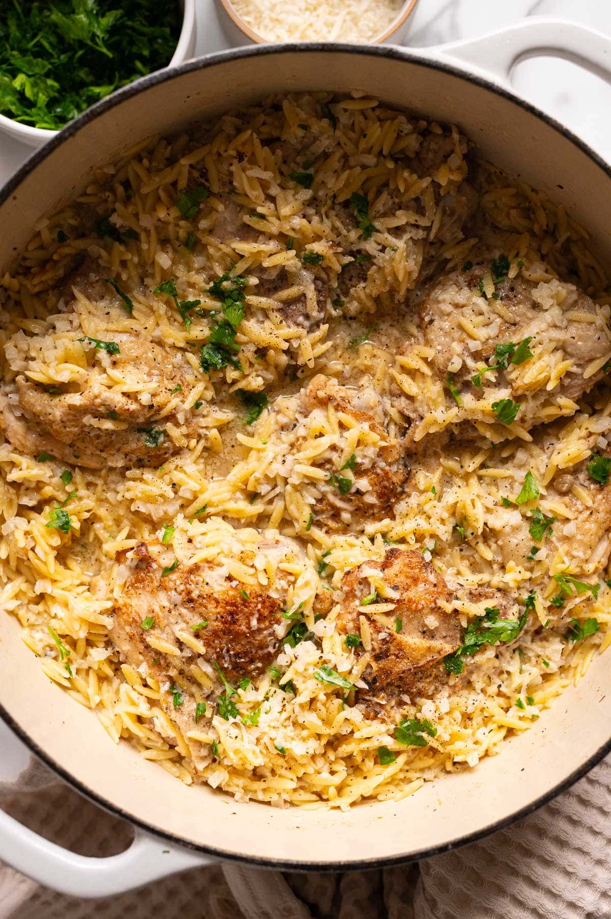 One pot lemon chicken orzo garnished with parsley in a Dutch oven.