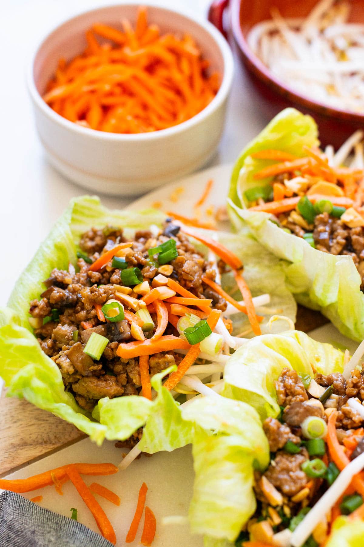 Asian turkey lettuce wraps garnished with green onion and peanuts and served on a platter.