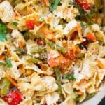 Chicken pasta primavera garnished with Parmesan cheese in a pot.