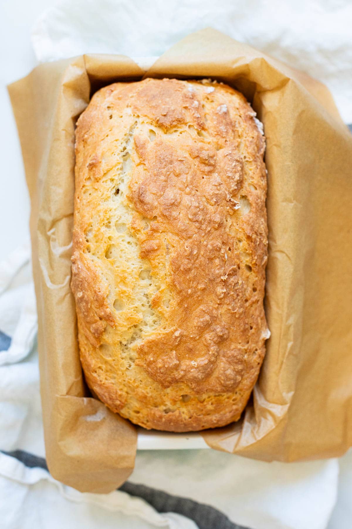 A loaf of bread in parchment lined loaf pan.