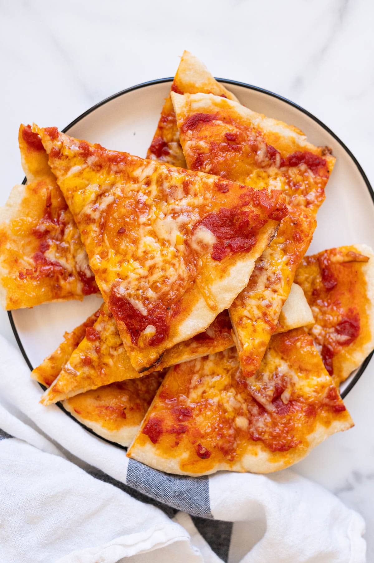 Greek yogurt pizza crust with marinara and cheese slices on a plate.