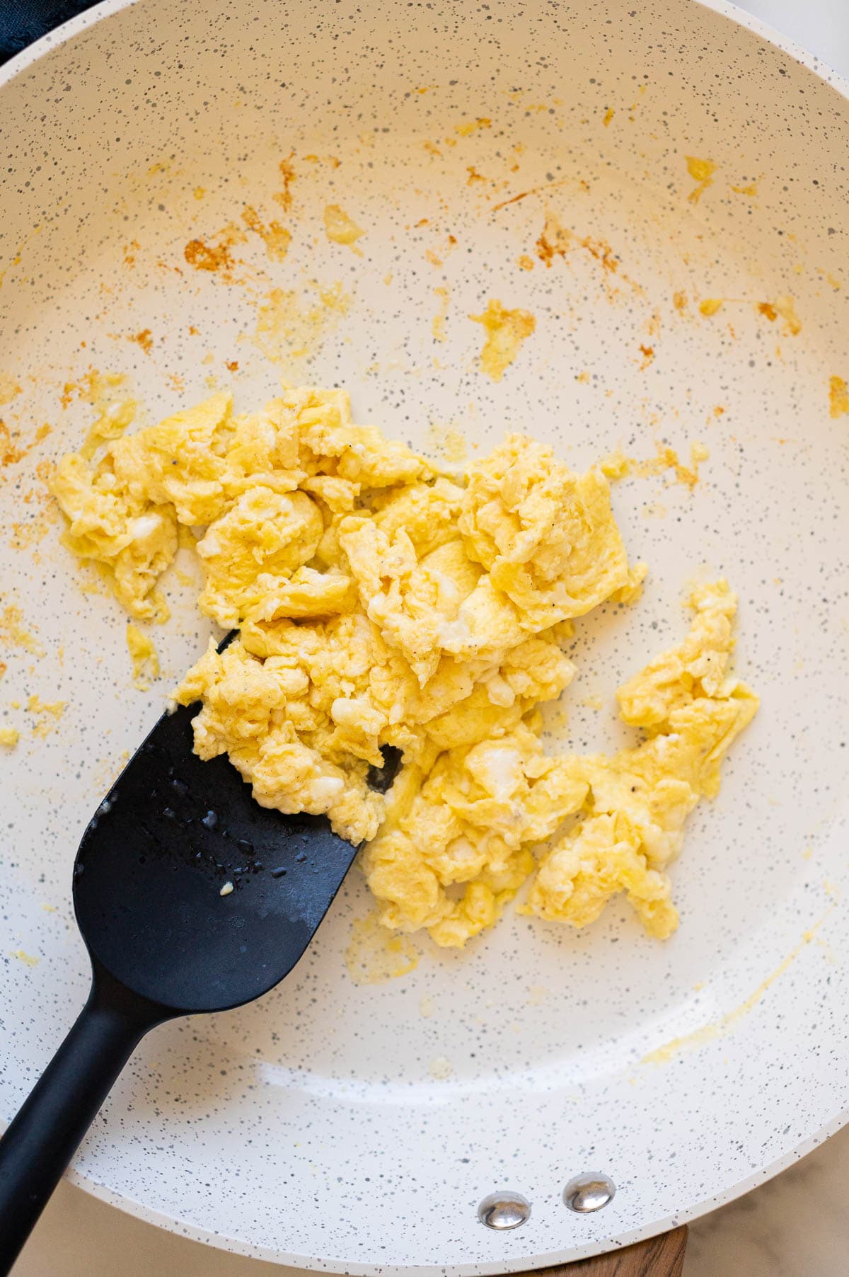 Cottage cheese scrambled eggs in a skillet with spatula.