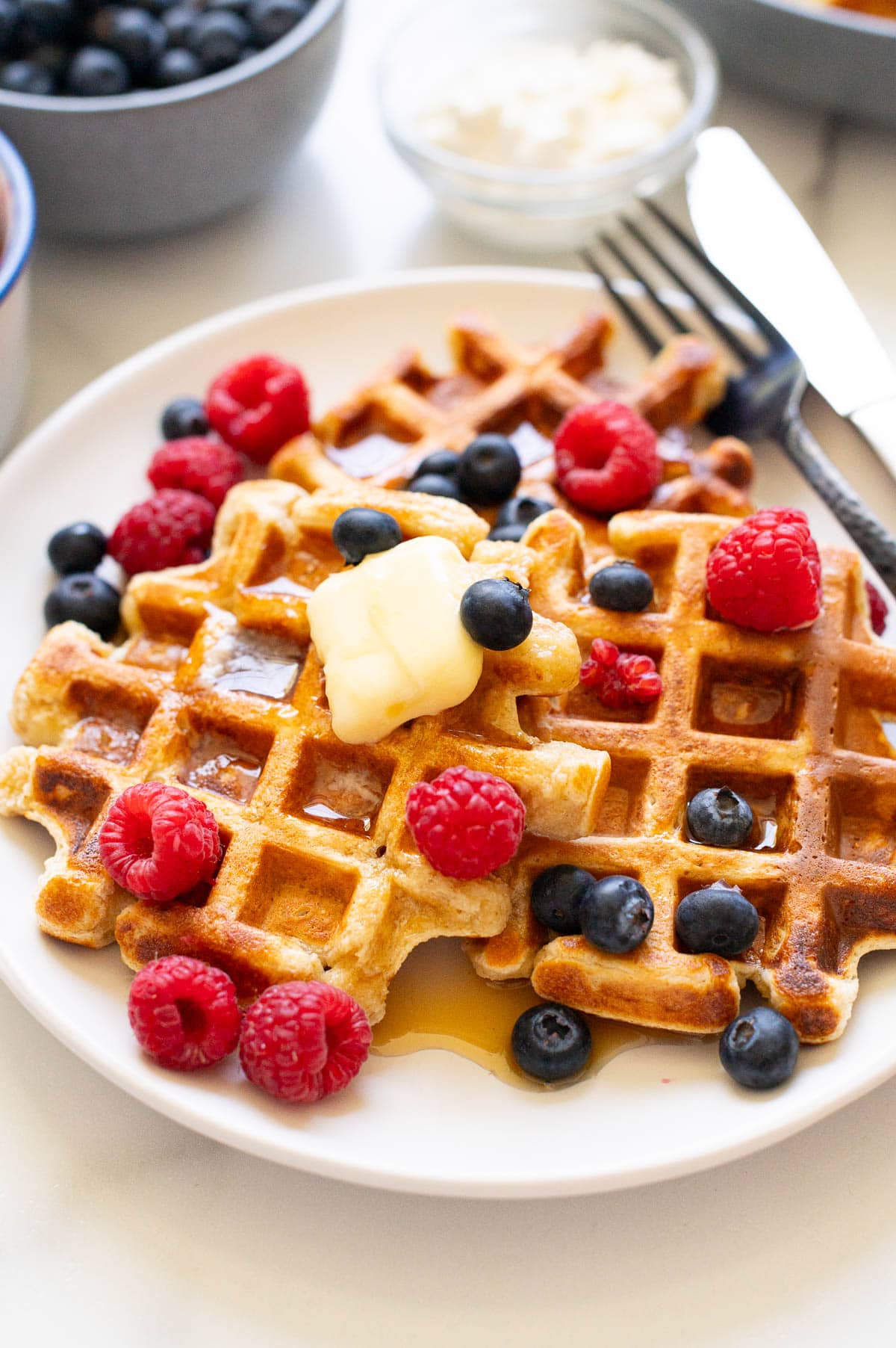 Side view of cottage cheese waffles with toppings on a plate.