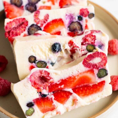 Protein frozen yogurt bars with strawberries, raspberries and blueberries on a plate.