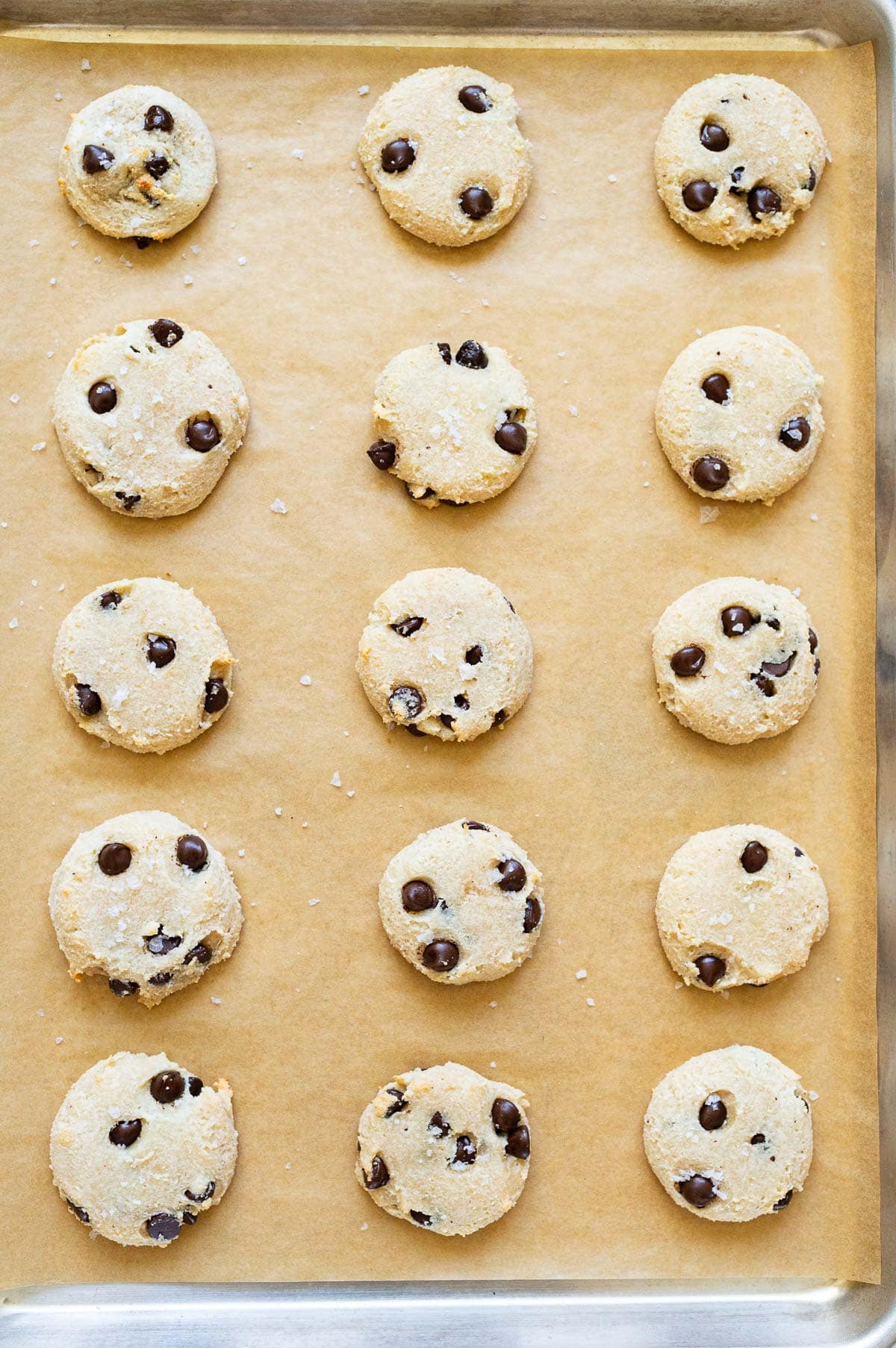 Baked chocolate chip cookies on a baking sheet lined with parchment paper.