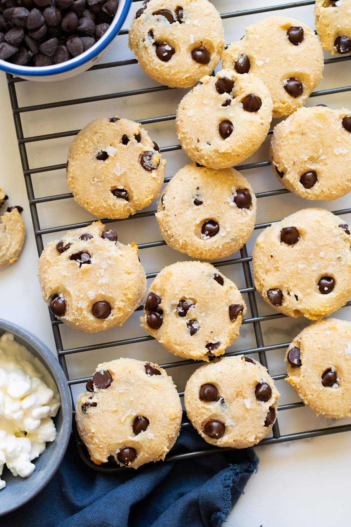 Cottage cheese cookies when a cooling rack. Cottage cheese and chocolate chips in bowls.