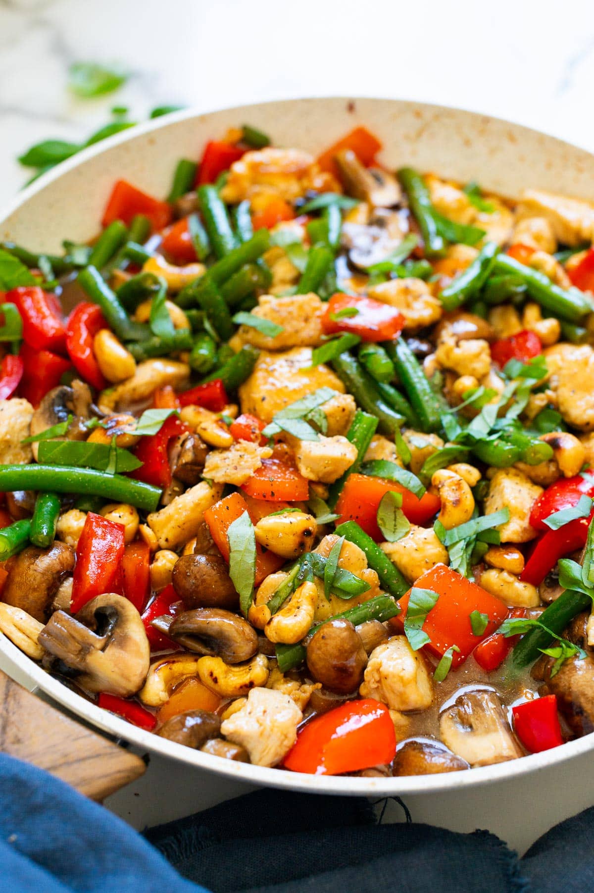 Side view of basil cashew chicken skillet in sauce.