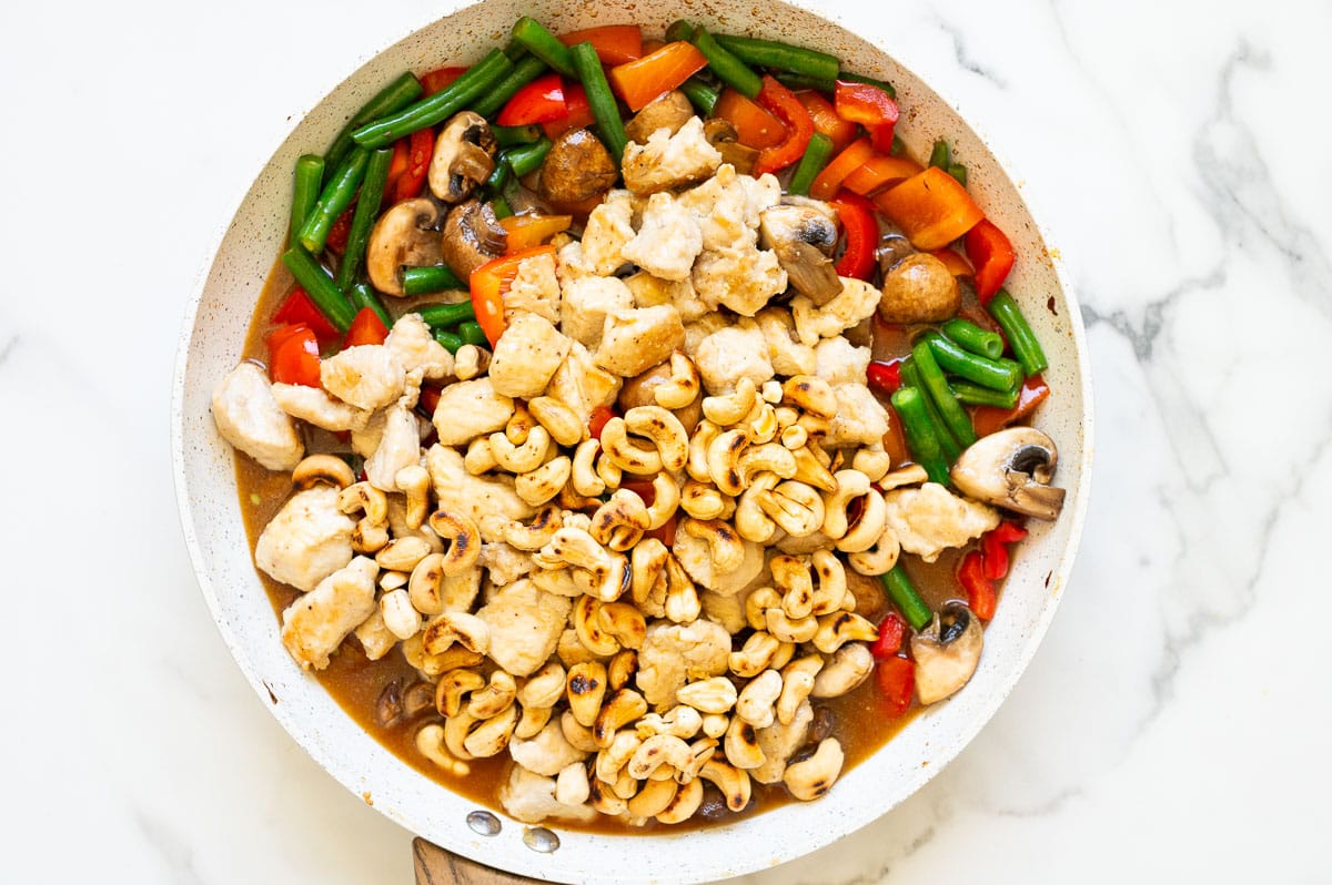 Cooked chicken, vegetables and cashew nuts combined with the sauce in the skillet.