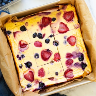 Baked yogurt with berries cut into nine slices in a baking dish.