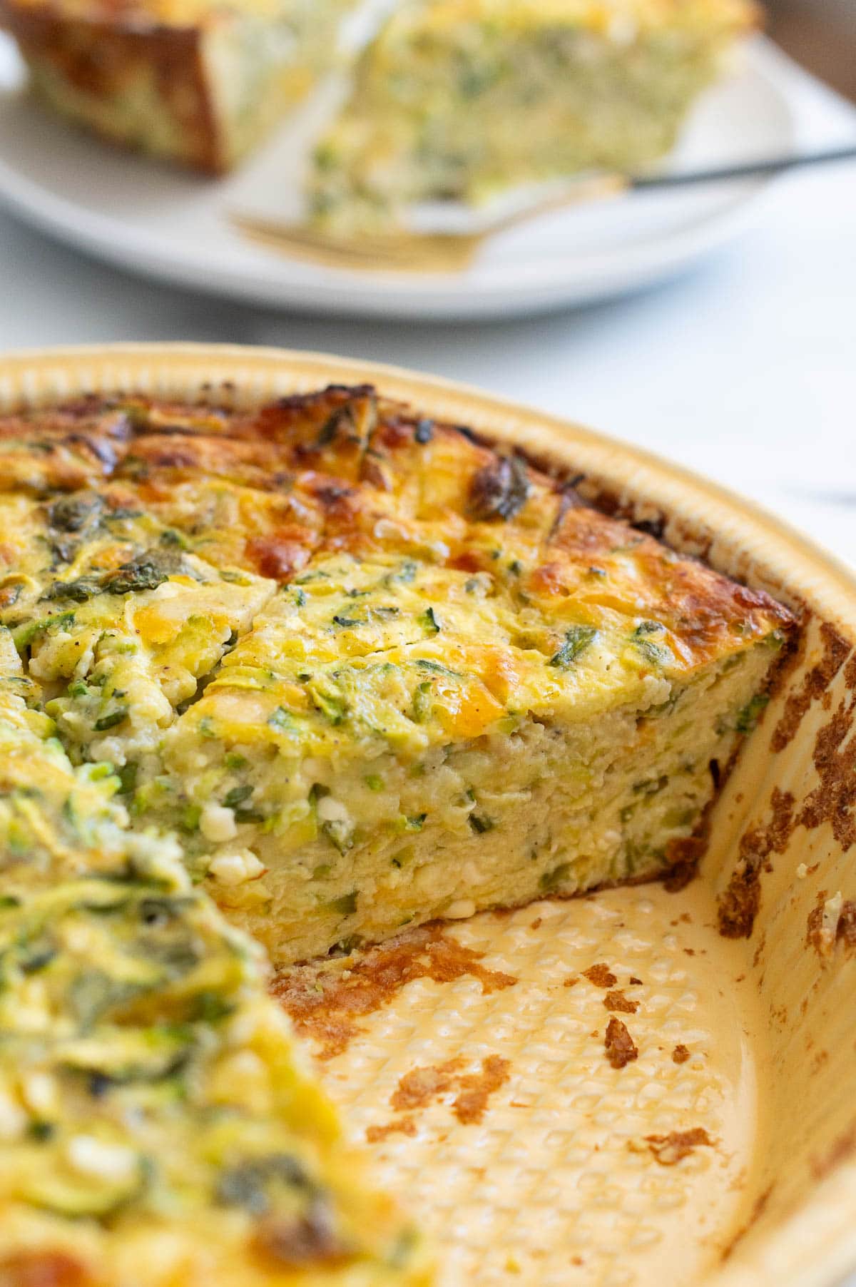 Sliced quiche in a pie plate showing texture inside.