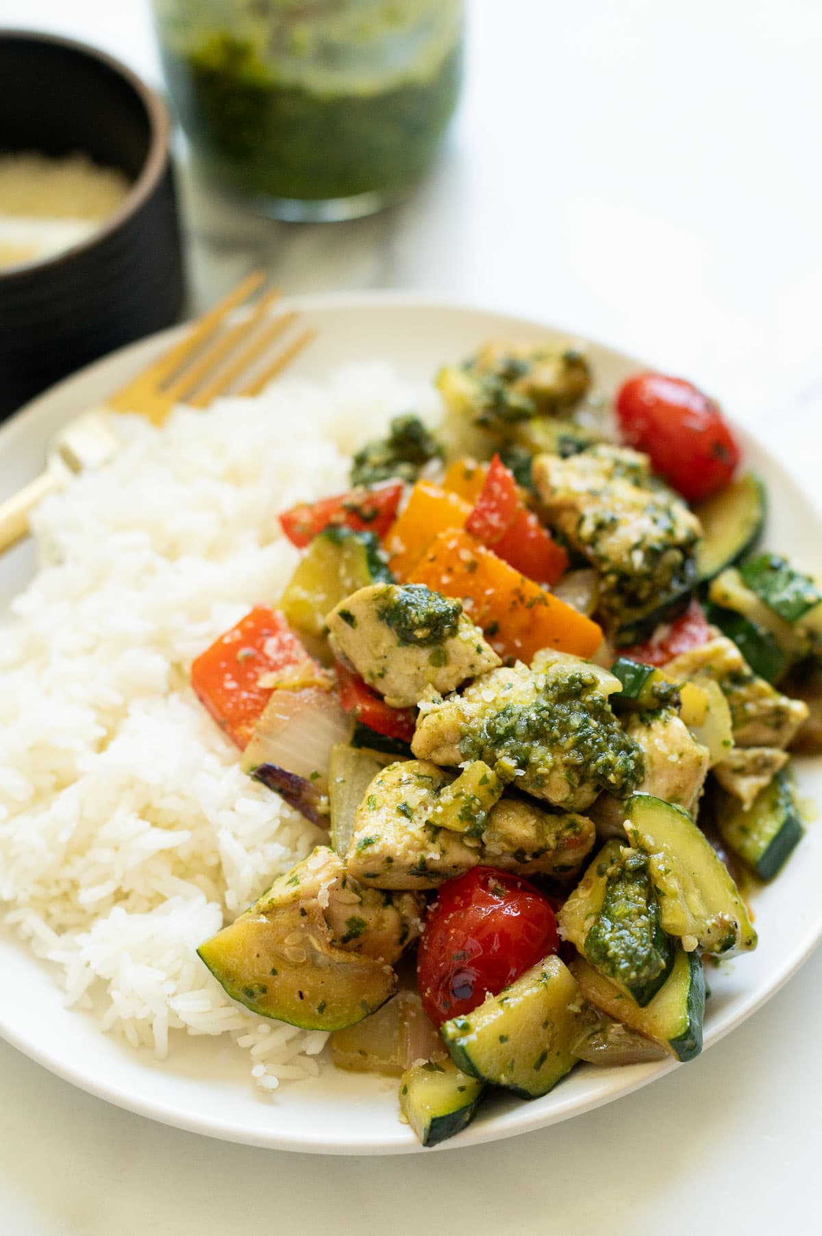 Side view of chicken and veggies served with rice on a plate.