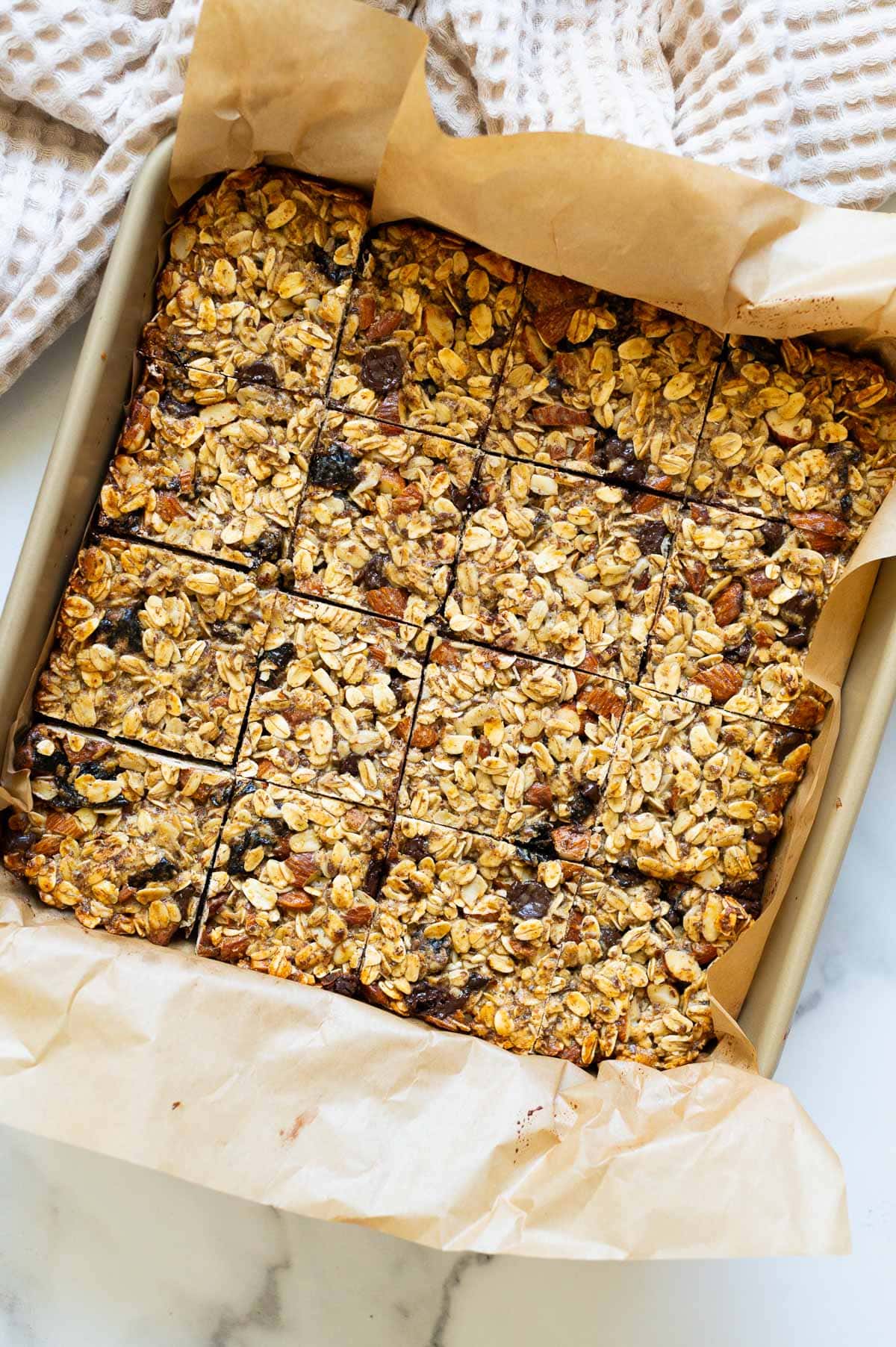 16 cut up protein granola bars in a baking dish lined with parchment paper.