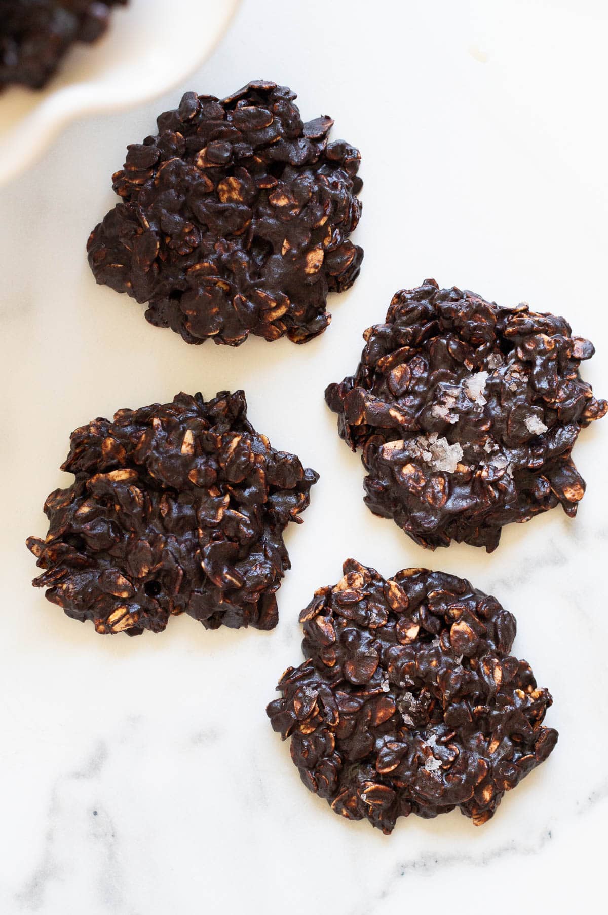 Four healthy no bake cookies on a counter. One sprinkled with sea salt.