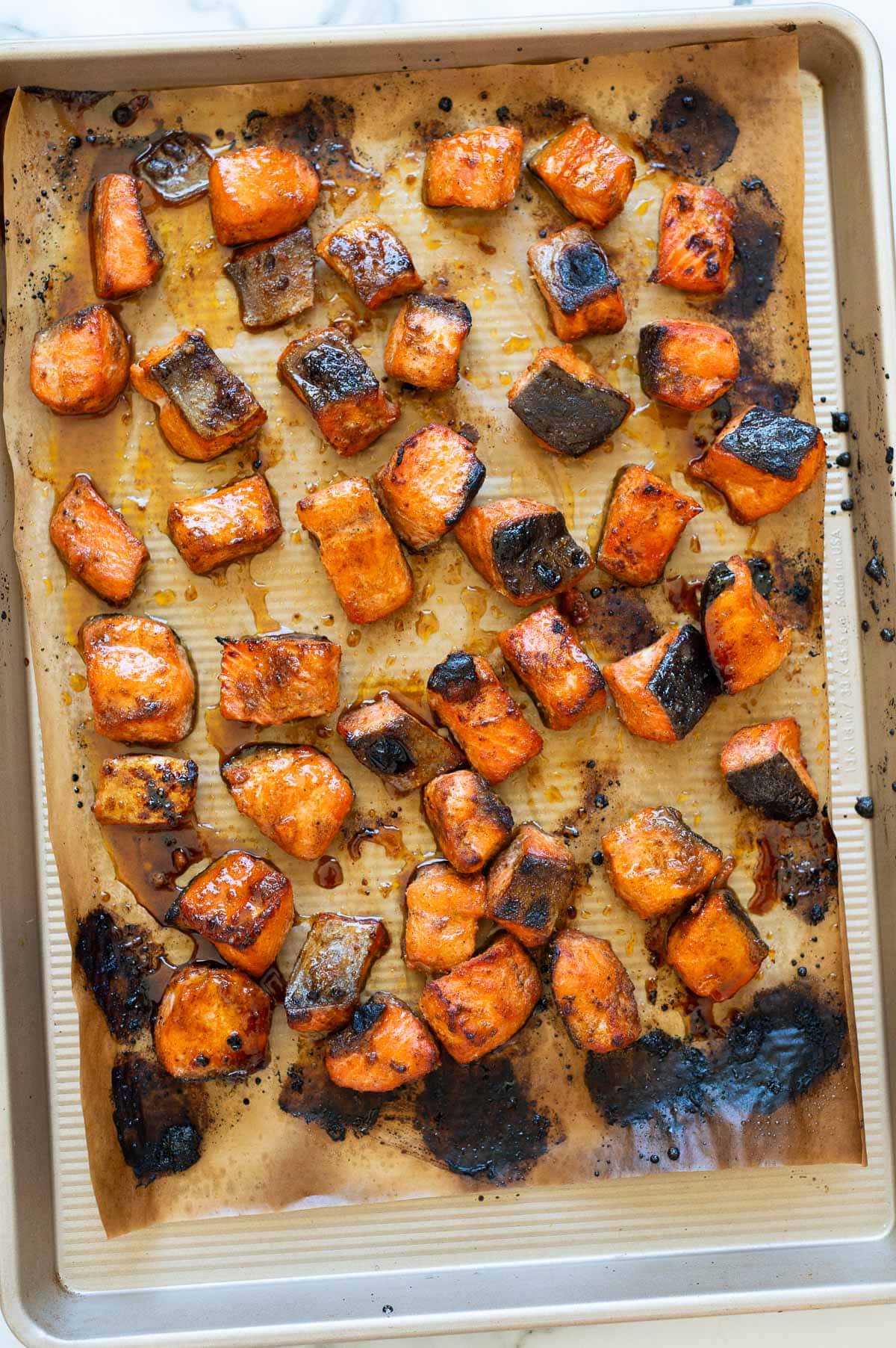 Hot honey salmon bites on parchment paper lined baking sheet.