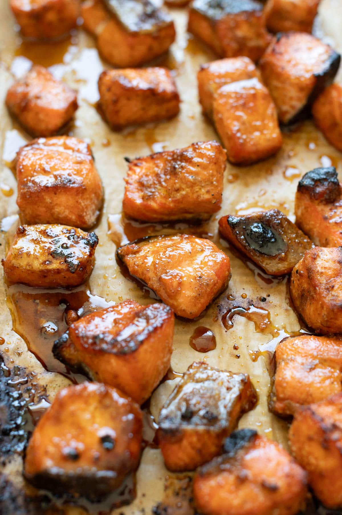 Side view of hot honey salmon bites on baking sheet.