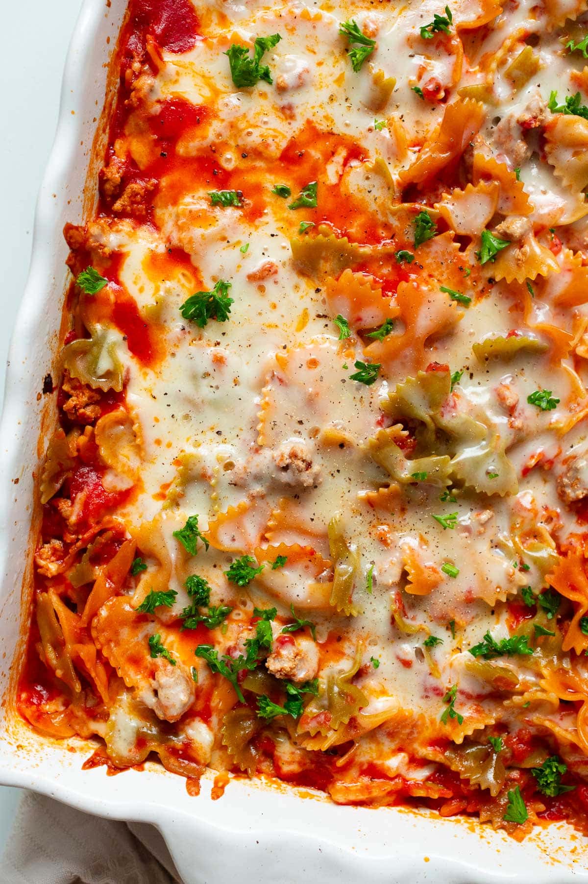 No boil pasta bake with melted cheese and parsley on top in baking dish.