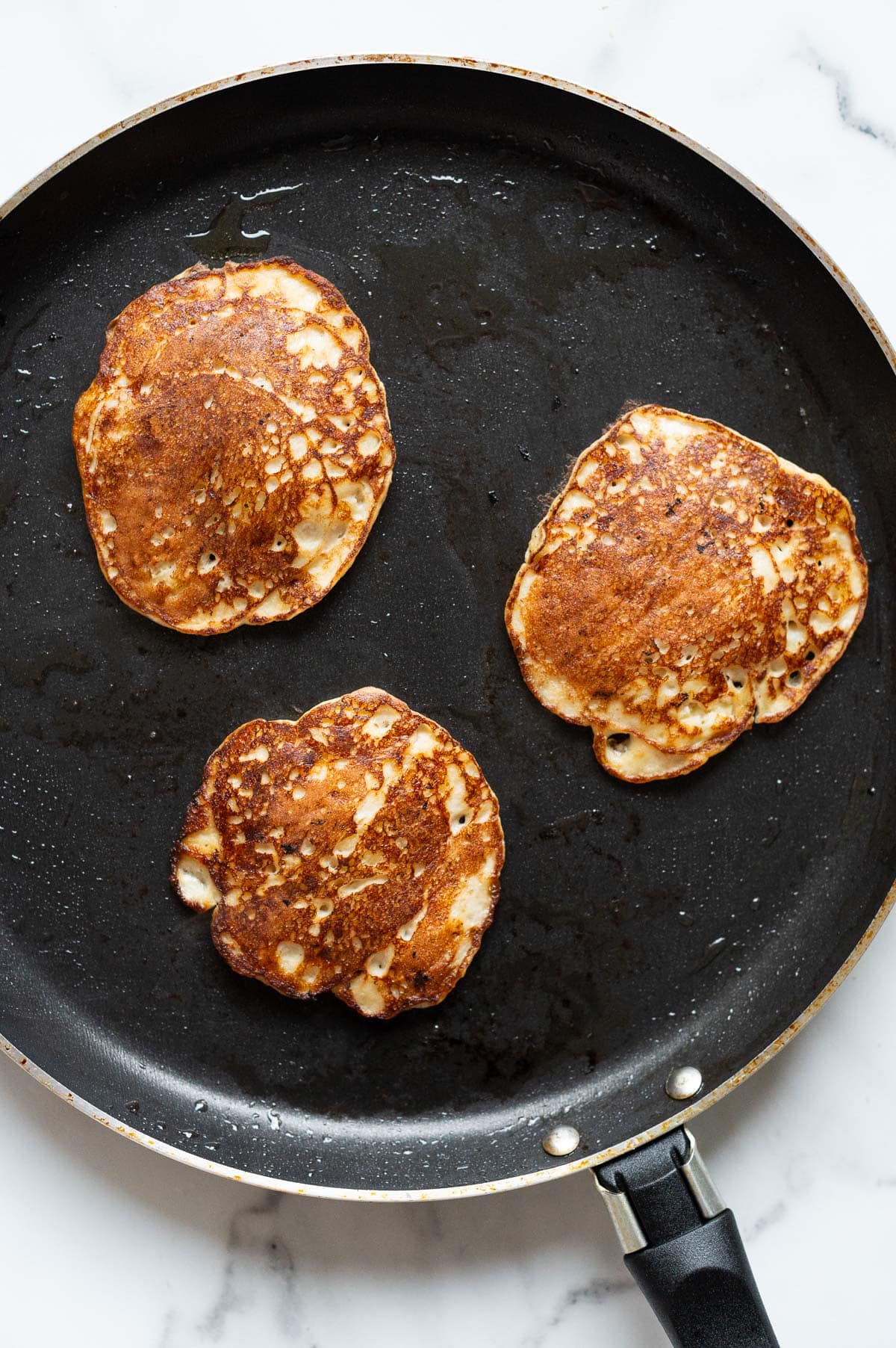 Three pancakes in a skillet.