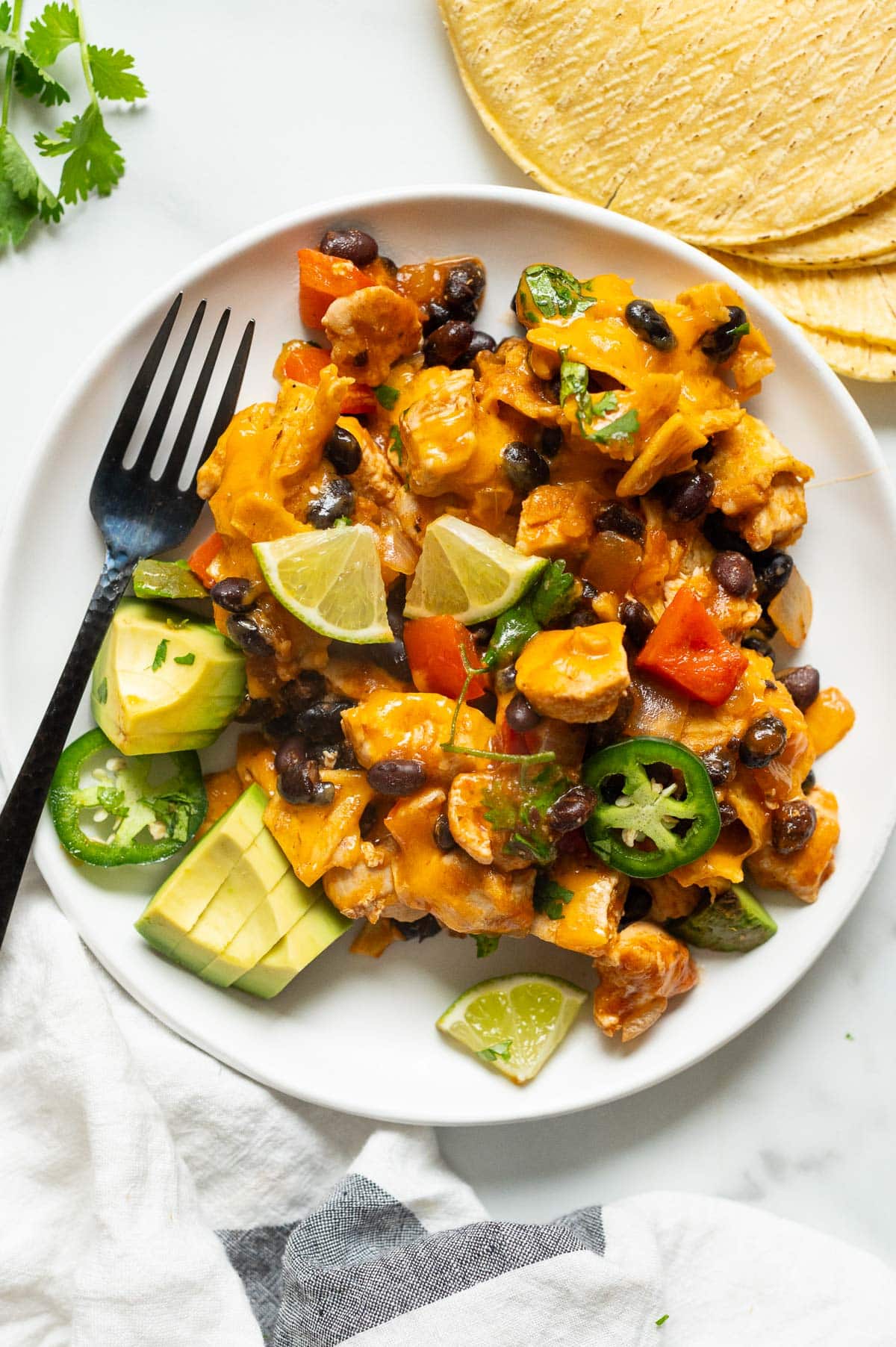 The constructed chicken enchiladas served with lime and avocado on a plate.