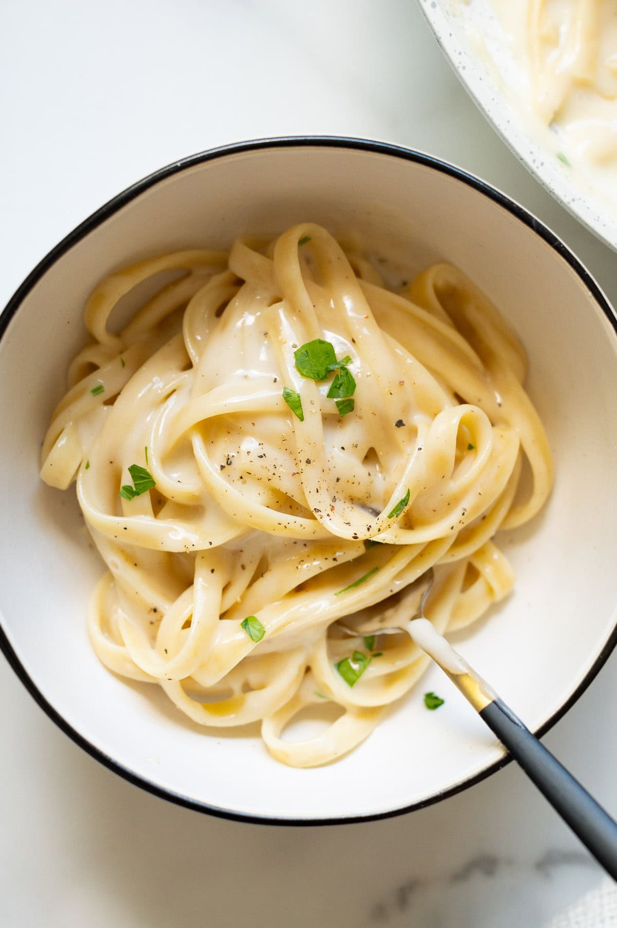 Cottage cheese alfredo garnished with parsley and black pepper in a bowl.