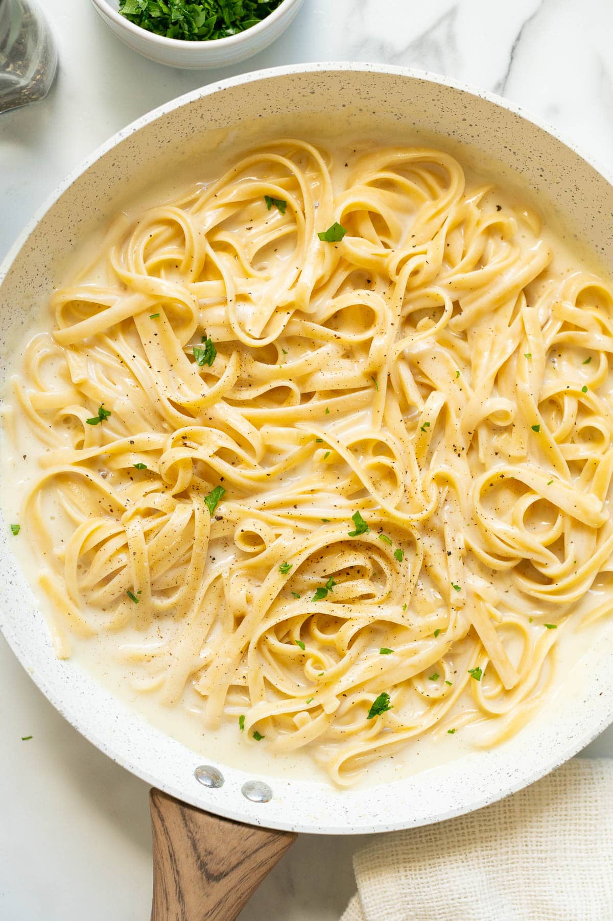 Cottage cheese alfredo garnished with parsley in white skillet.