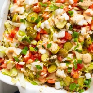 Big mac casserole with lettuce, pickles, tomatoes and big mac sauce in a baking dish.