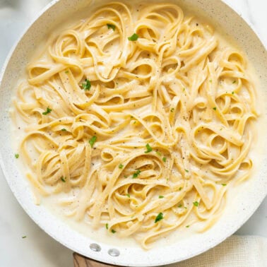 Cottage cheese alfredo garnished with parsley in white skillet.