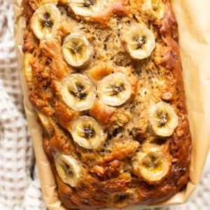 Greek yogurt banana bread garnished with banana slices in a loaf pan.