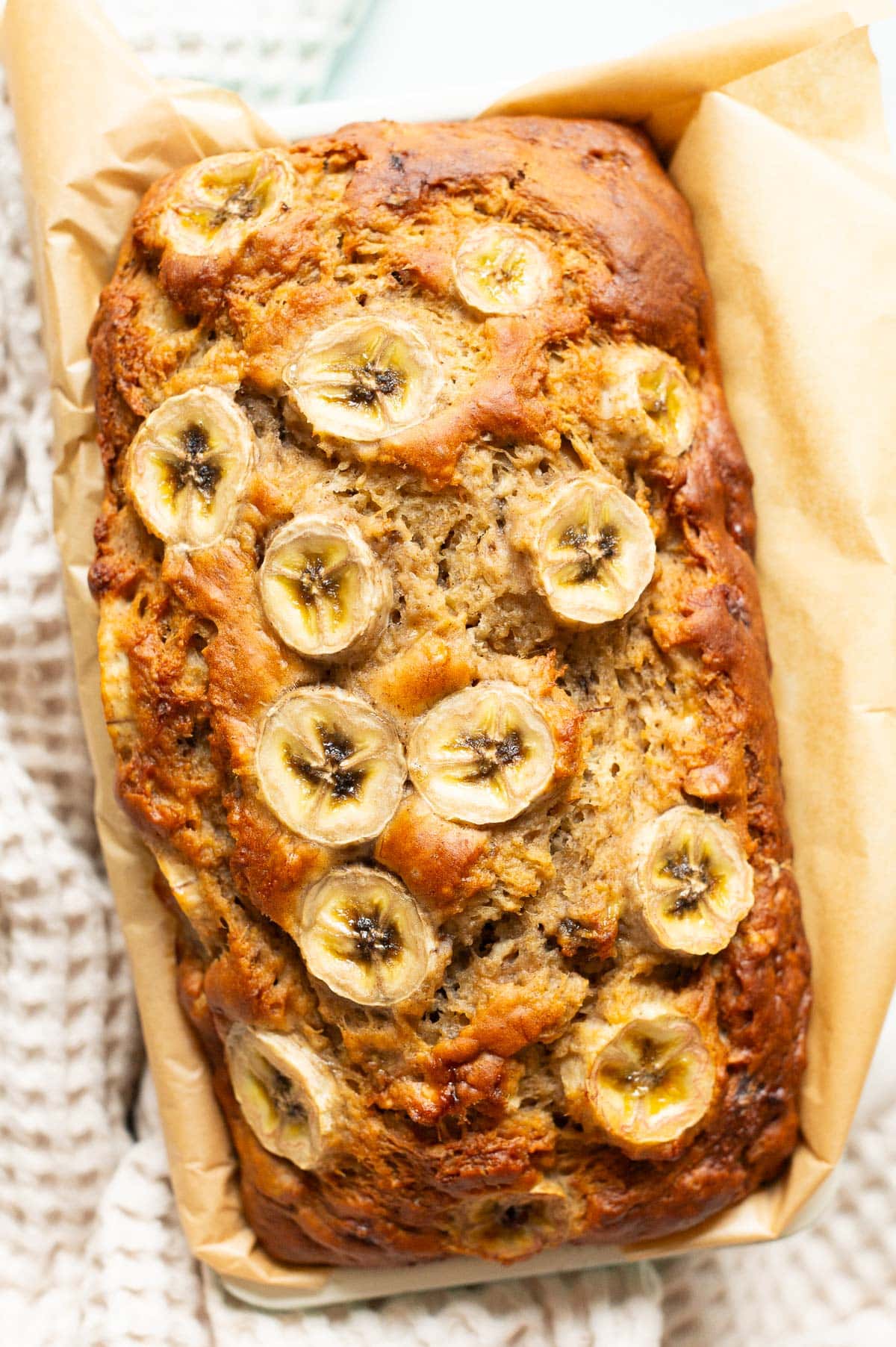 Greek yogurt banana bread garnished with banana slices in a loaf pan.