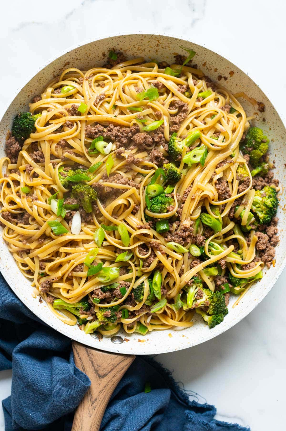 Noodles with Mongolian ground beef, broccoli  green onion in a skillet.