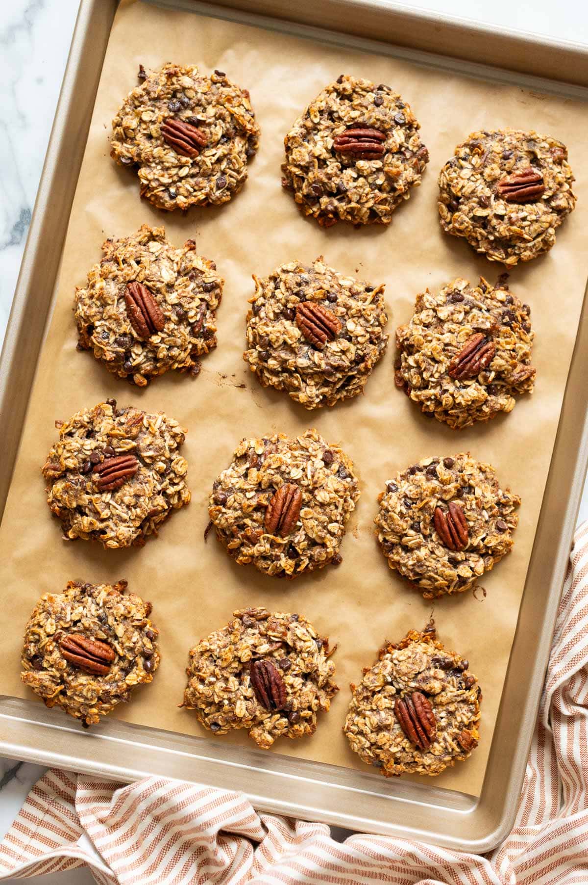 12 breakfast cookies garnished with pecans on a baking sheet.