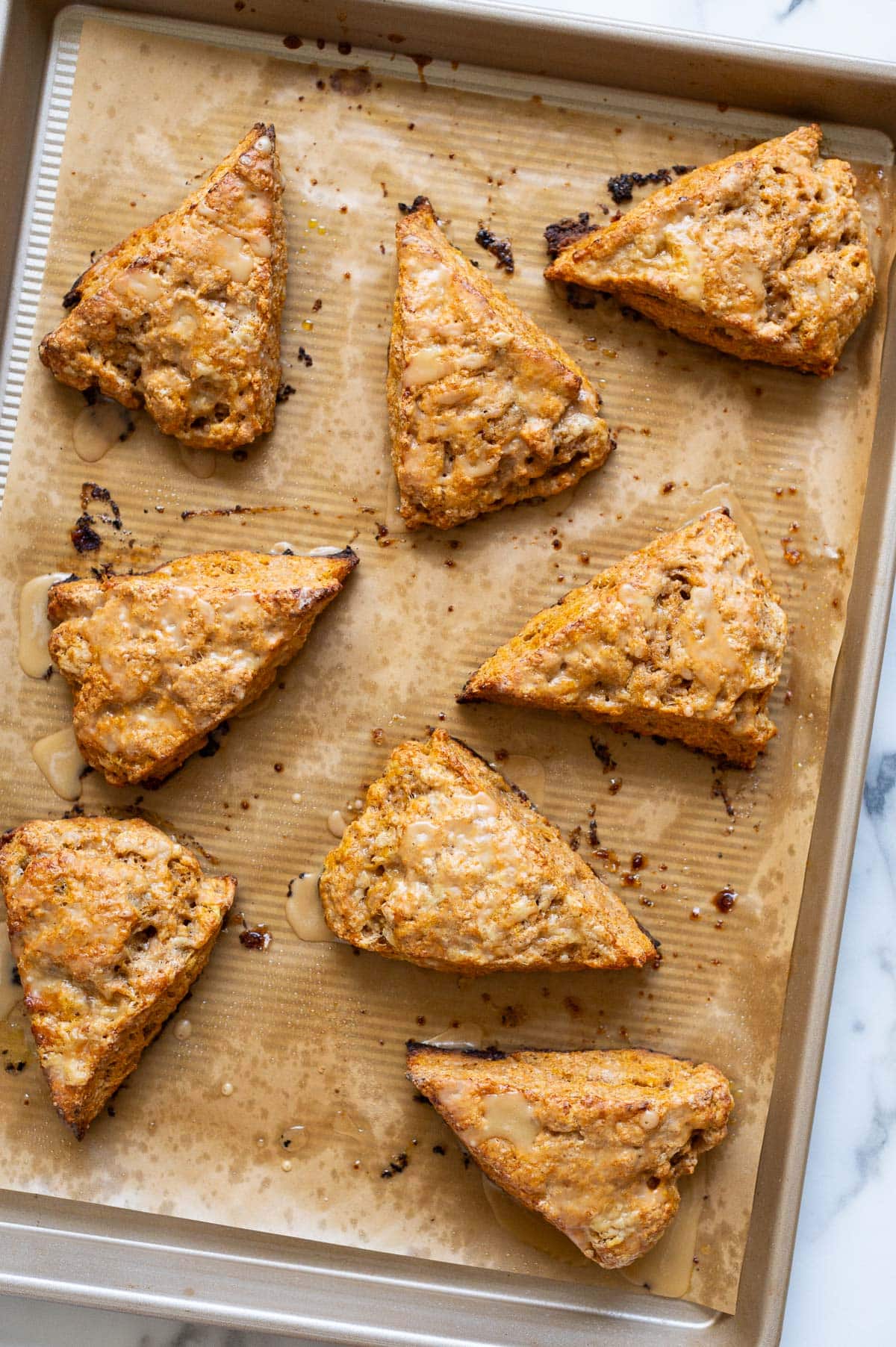 Pumpkin scones with maple glaze on a baking sheet.